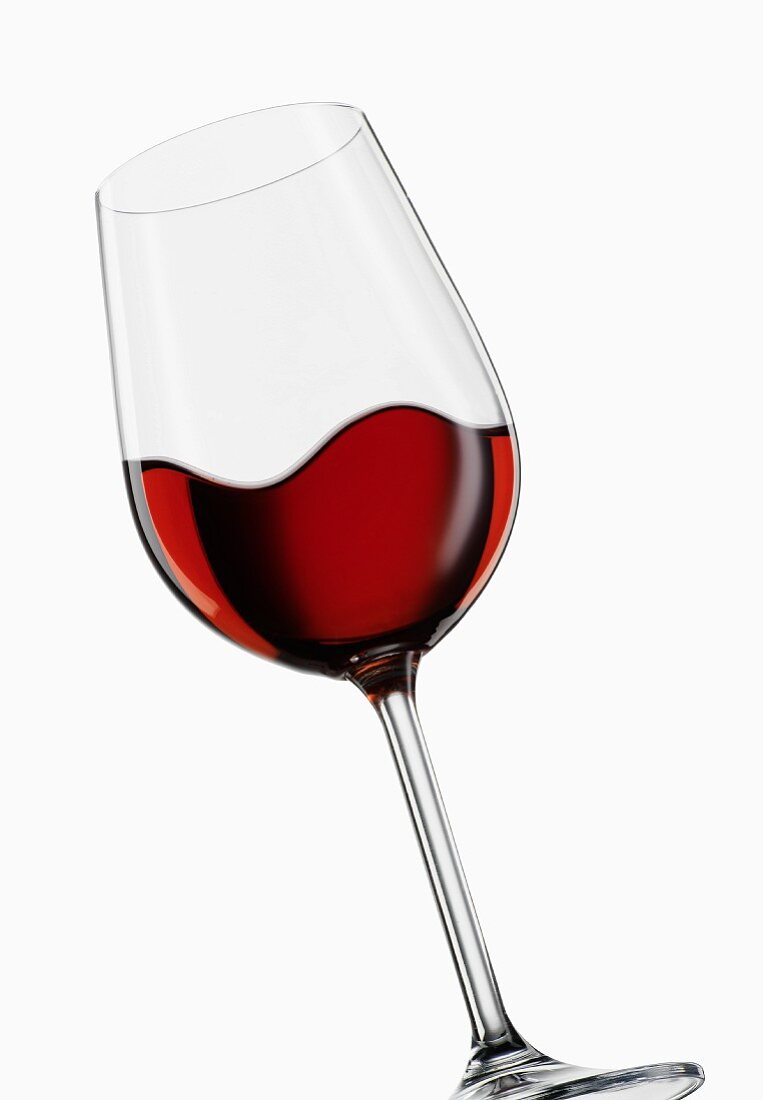 A tilted glass of red wine, moving