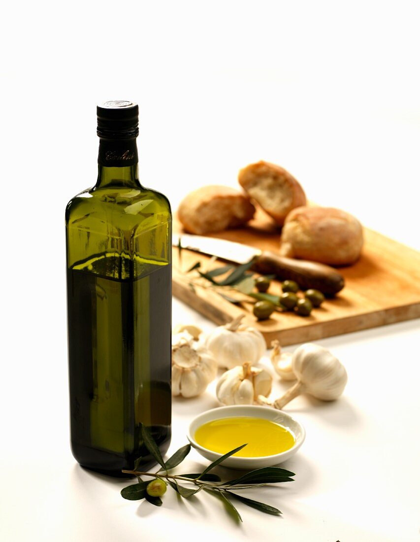 Eine Flasche Olivenöl mit Knoblauch, Oliven und Brot