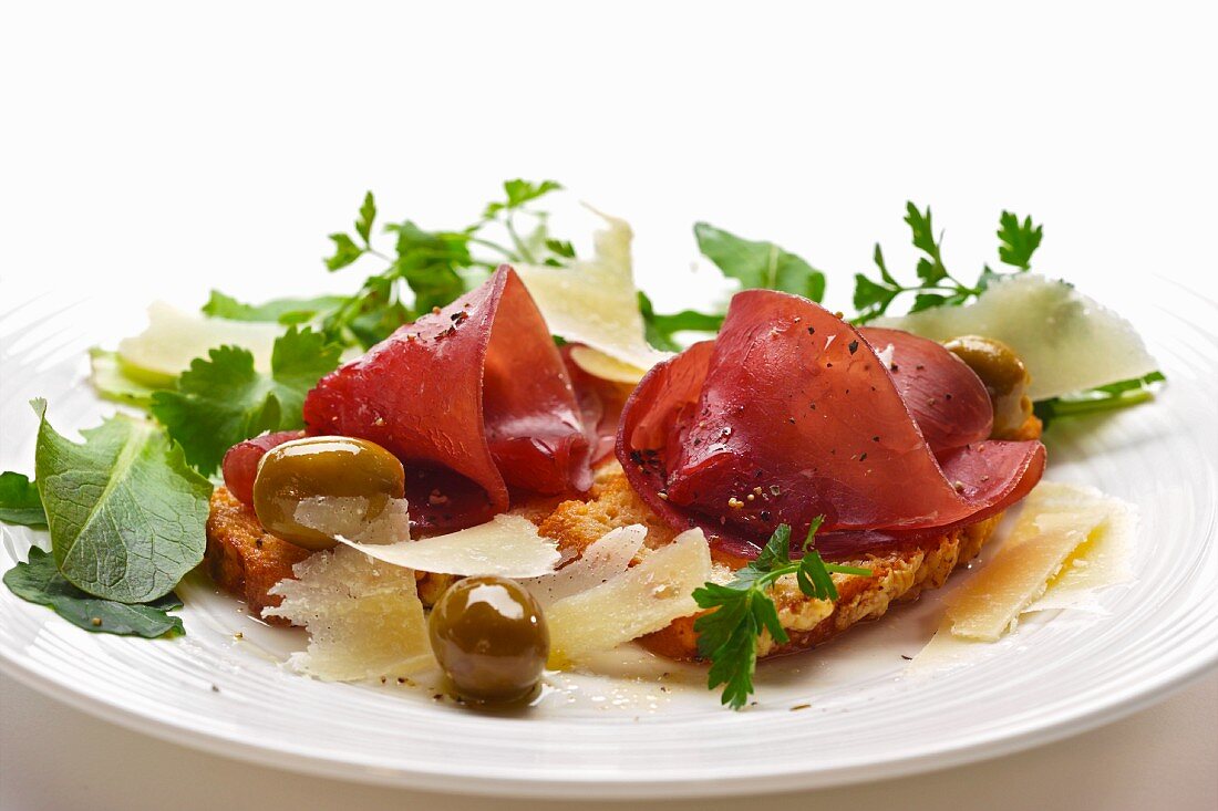 Bresaola auf Bruschetta mit Parmesan, Oliven und Blattsalat