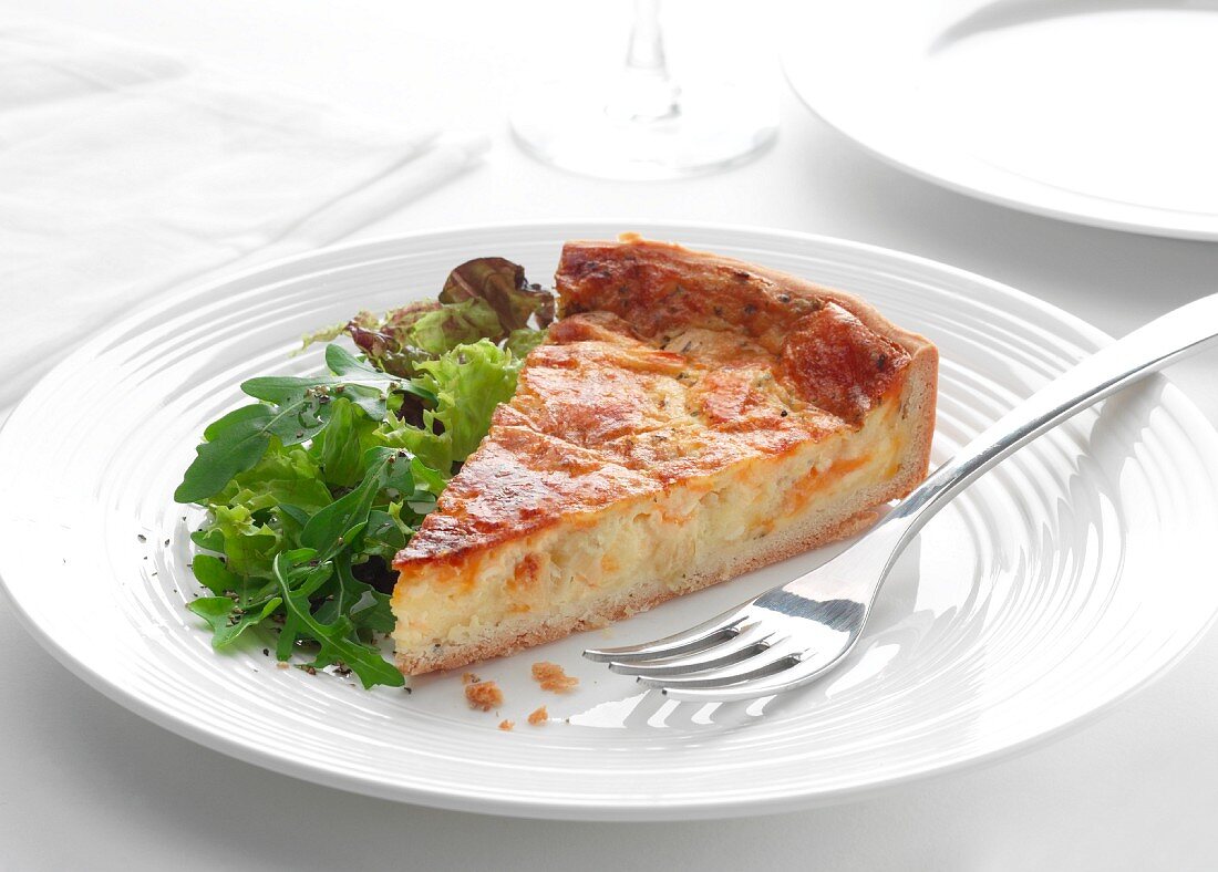 Ein Stück Käse-Schnittlauch-Quiche mit Rucolasalat