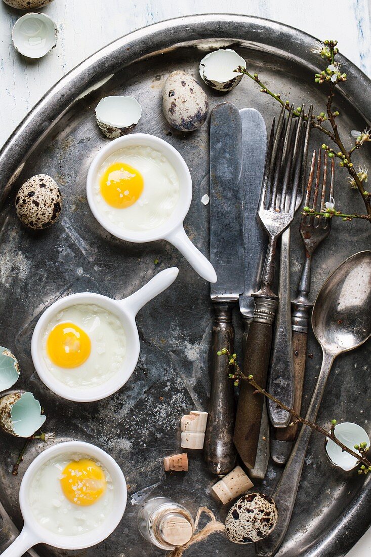 Top view on fried quail eggs with vintage tableware on old metal tray