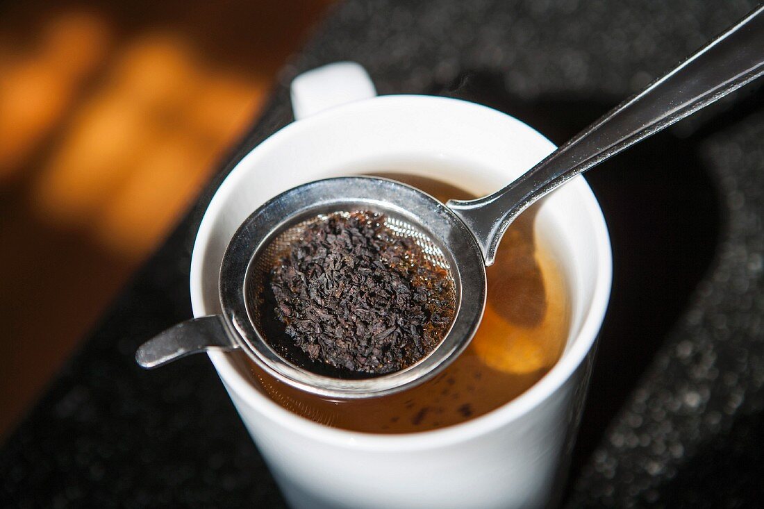 Teesieb mit Teeblättern in einer Teetasse