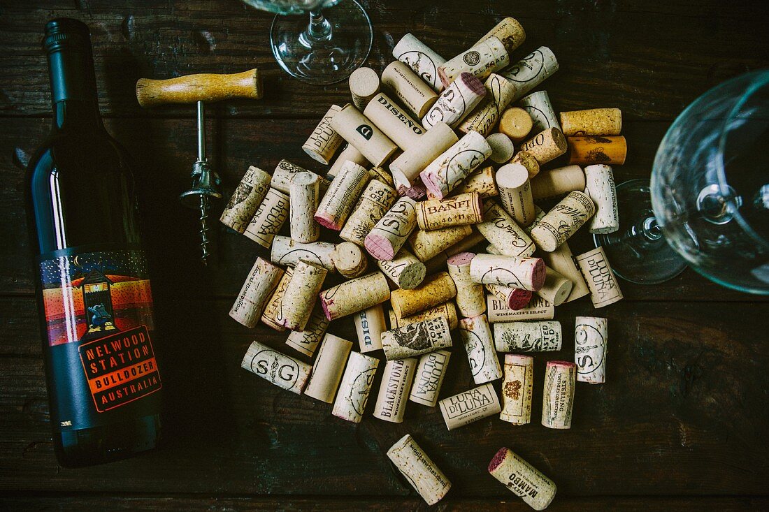 Assortment of Corks next to Wine Bottle, Wineglasses and Corkscrew