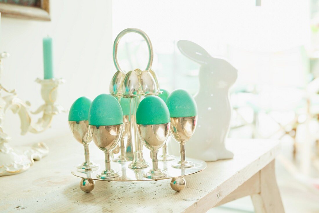 Green Easter eggs in silver egg cups on a table laid for Easter