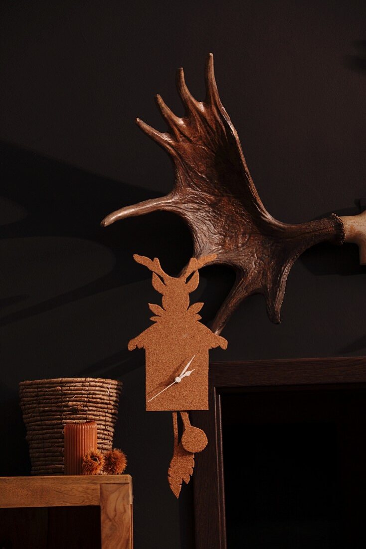 Cork wall clock next to partially visible antler on black wall