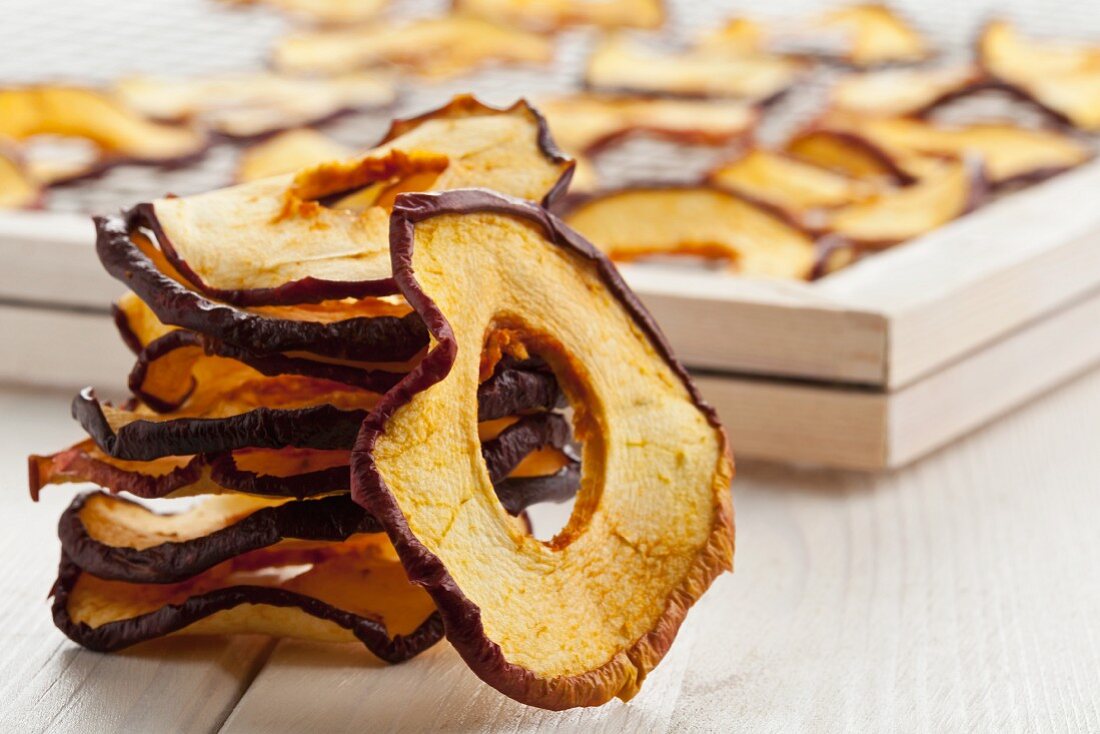 A stack of dried apple rings in front of a drying rack