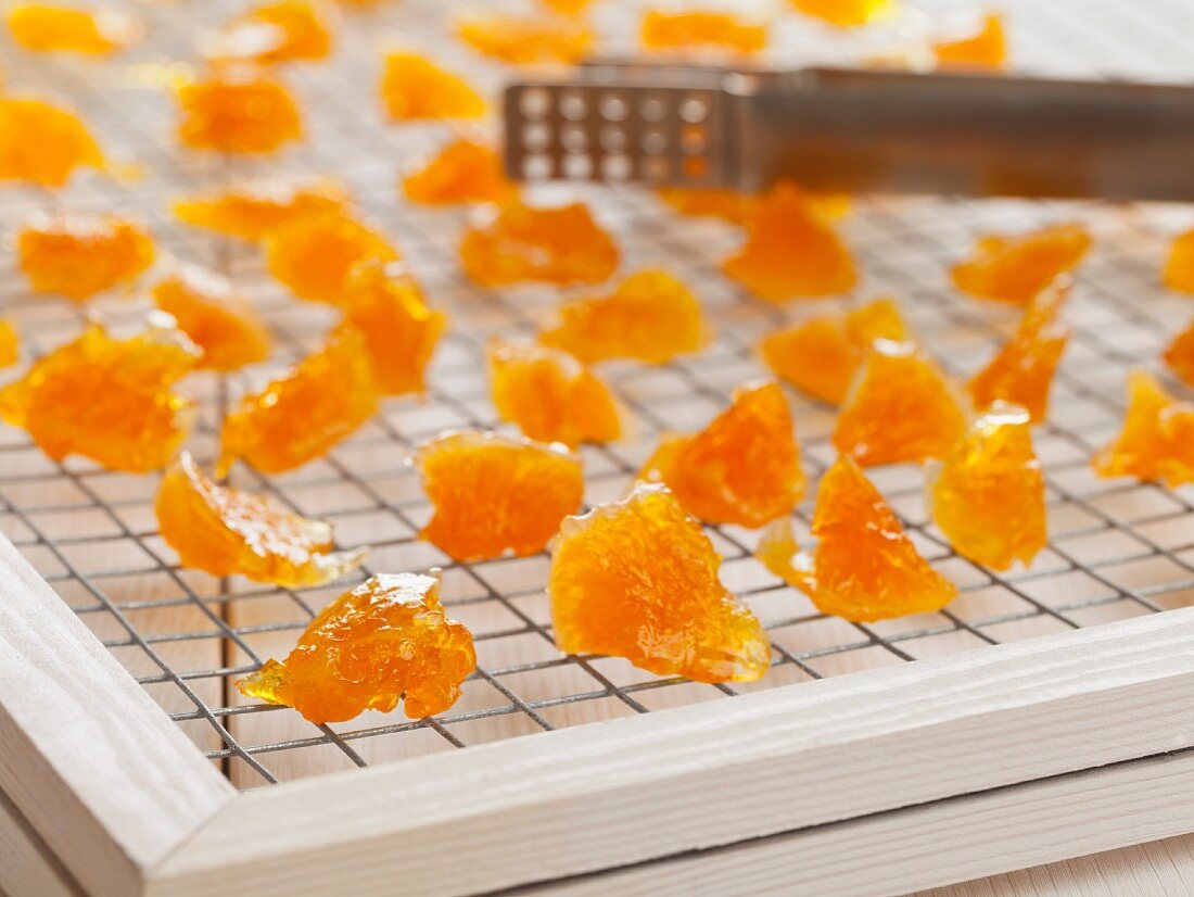 Candied orange pieces drying on a wire rack