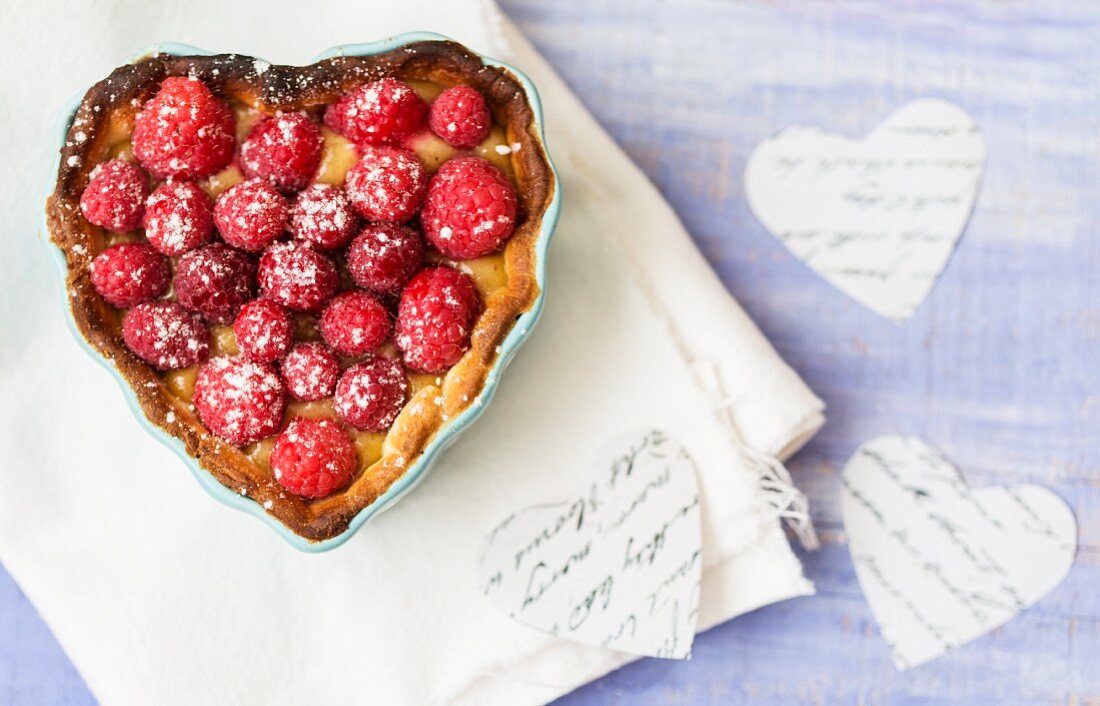 A raspberry tart in a heart-shaped baking tin