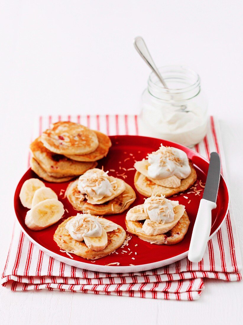 Raspberry pancakes topped with banana, vanilla yogurt and grated coconut