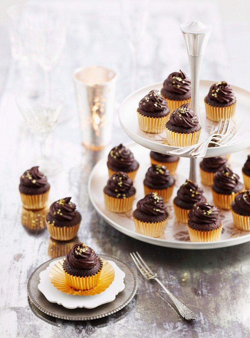 Mud cakes topped with ganache in praline cases on a cake stand