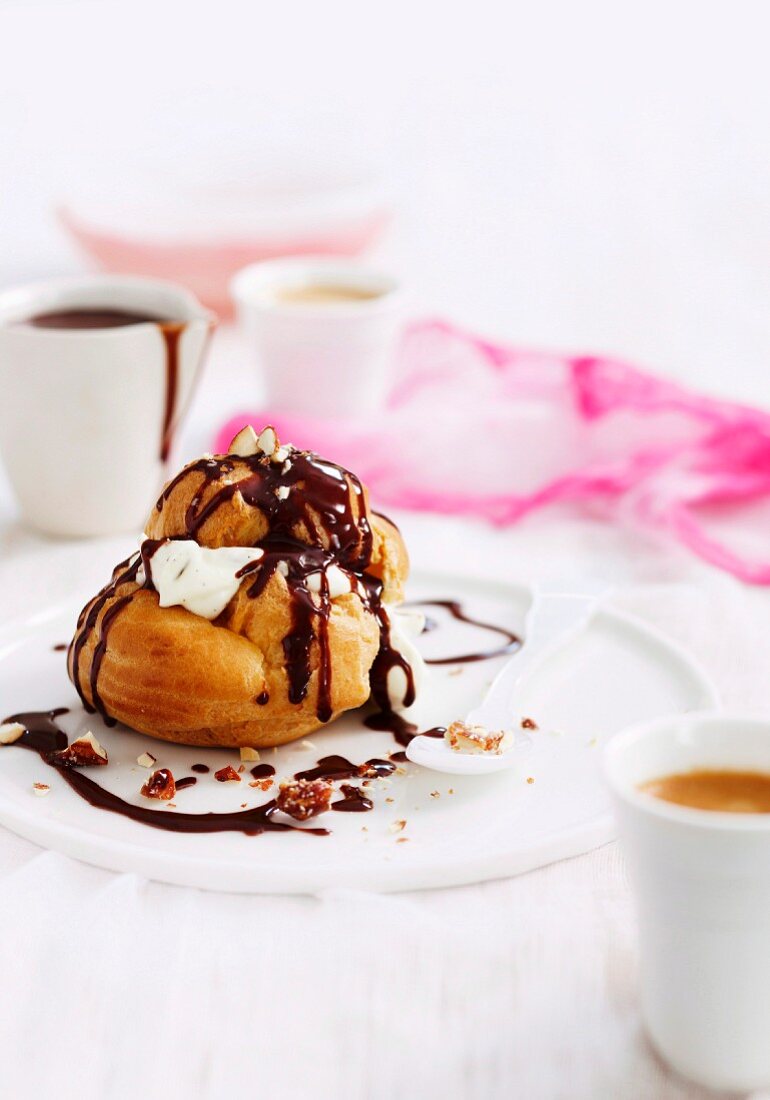 A profiterole with cream, chocolate sauce and almonds