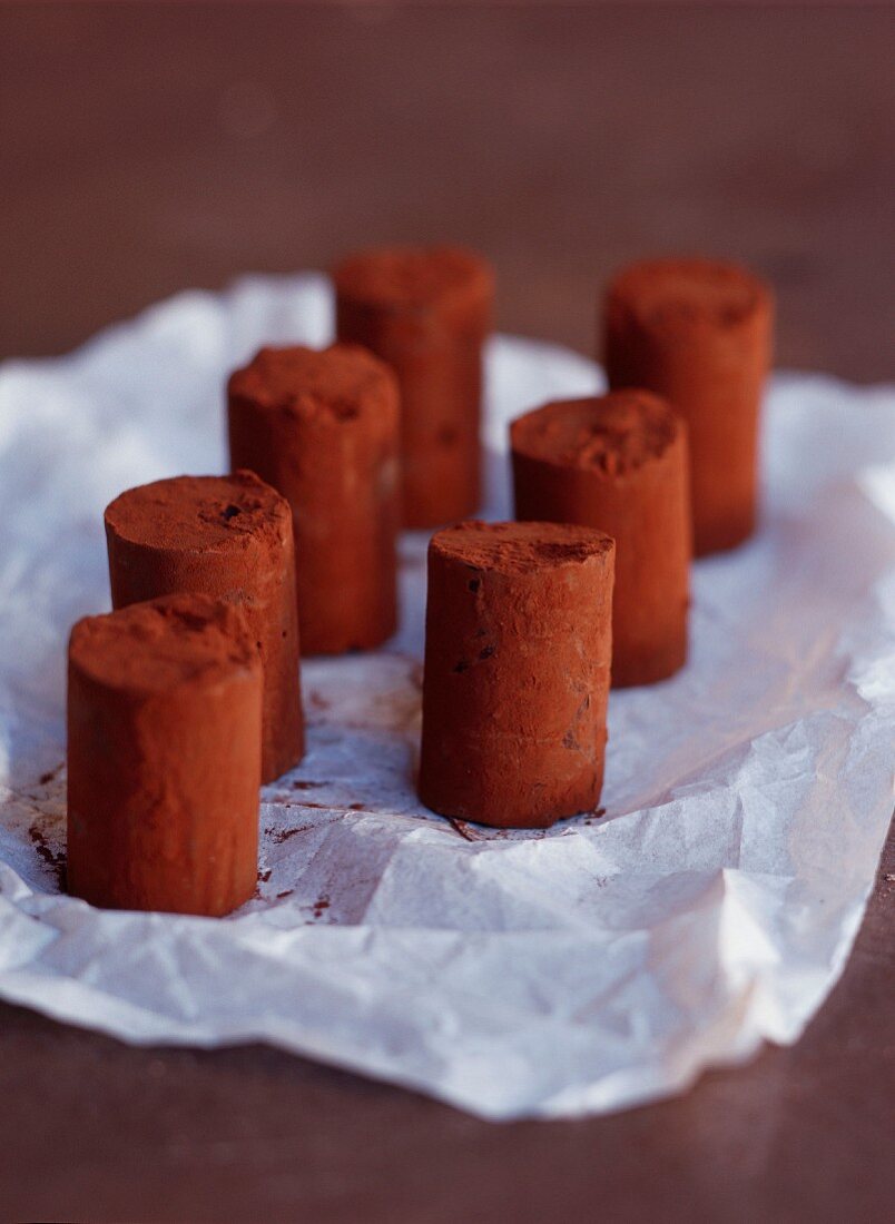 Schokoladenröllchen mit Kakaopulver auf zerknittertem Papier