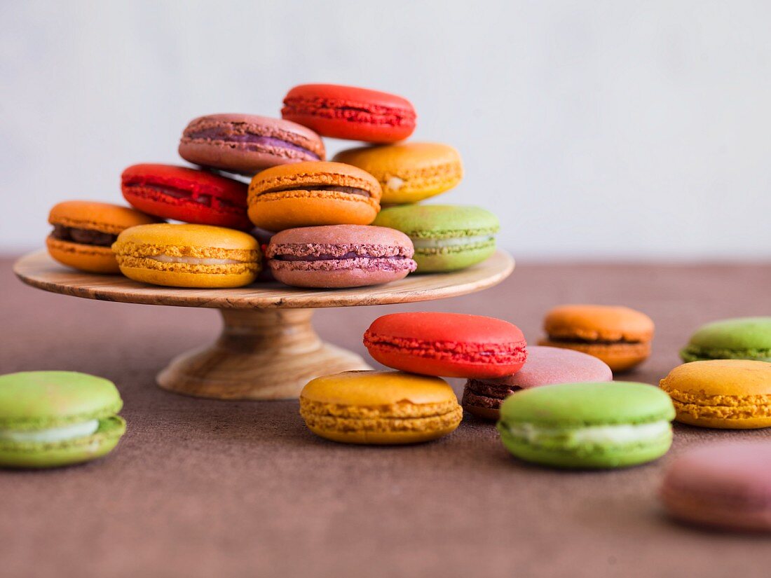 Verschiedenfarbige Macarons auf Kuchenständer und daneben