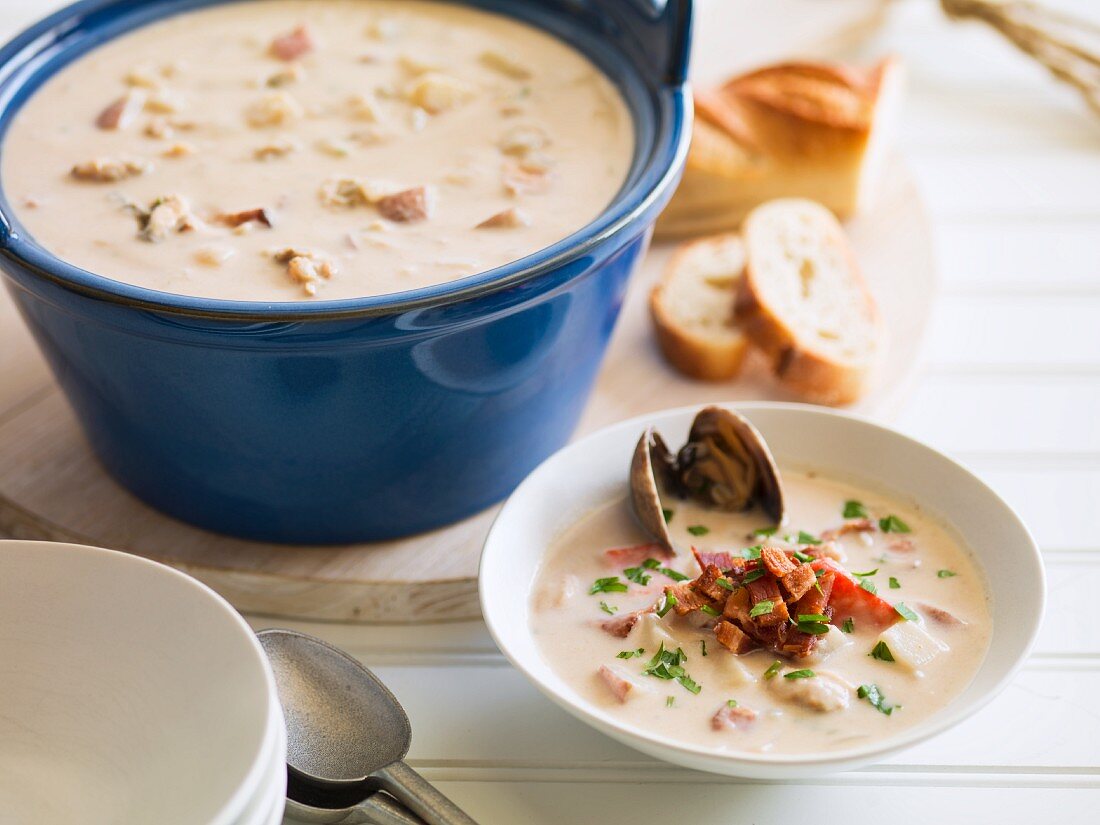 Fischsuppe, garniert mit Speck und Petersilie, im Kochtopf und Suppenteller