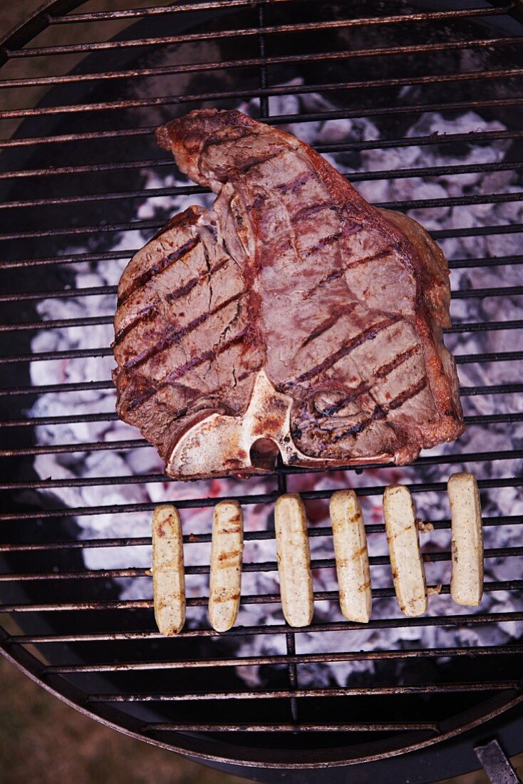 A T-bone steak and sausages on a barbecue