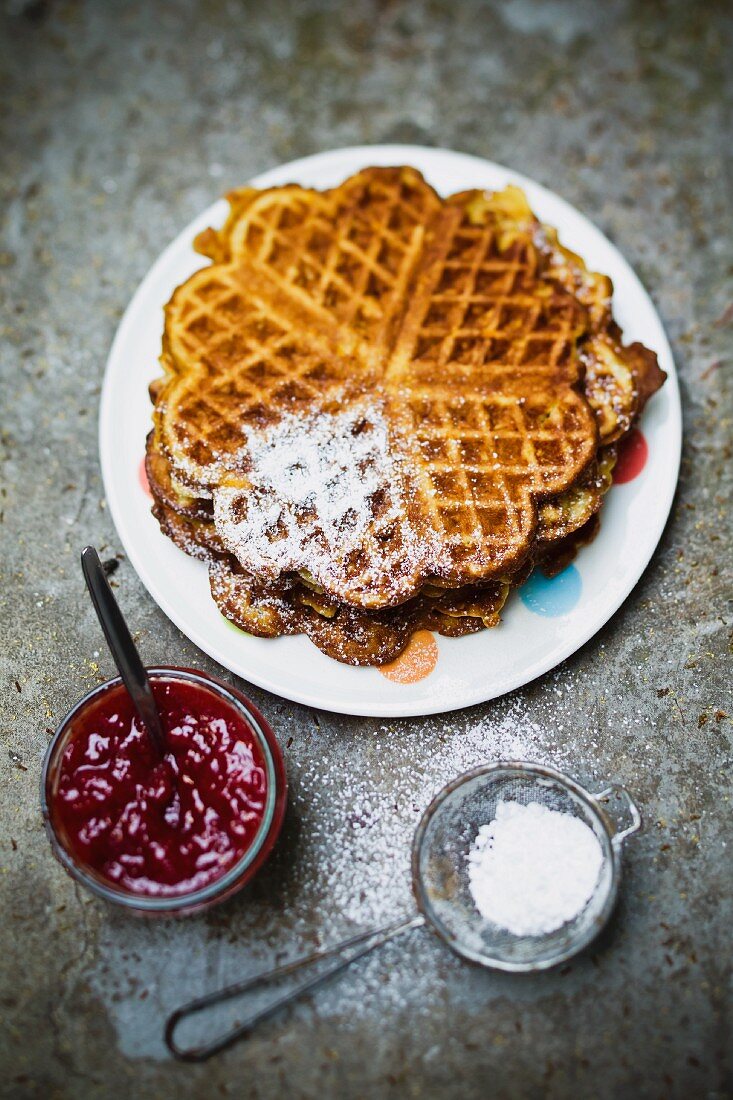 Waffles with icing sugar and strawberry jam