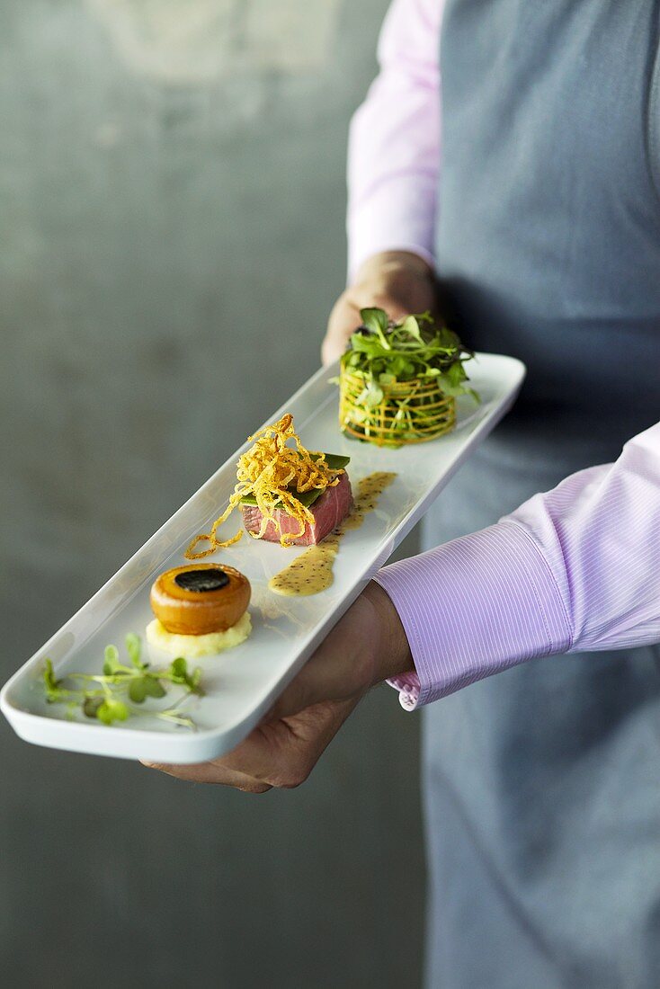 A chef presenting a mixed appetizer platter