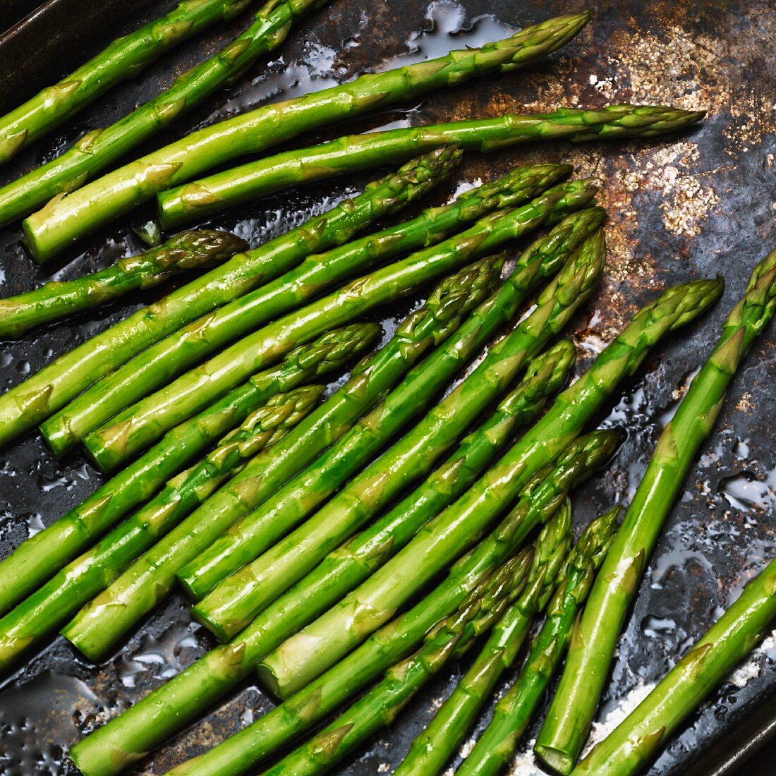 Green asparagus drizzled with olive oil on a baking tray