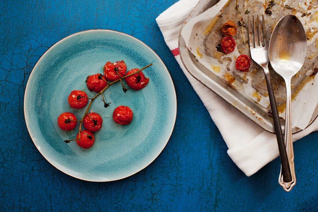 Slow roasted cherry tomaotes on a plate and a baking tray