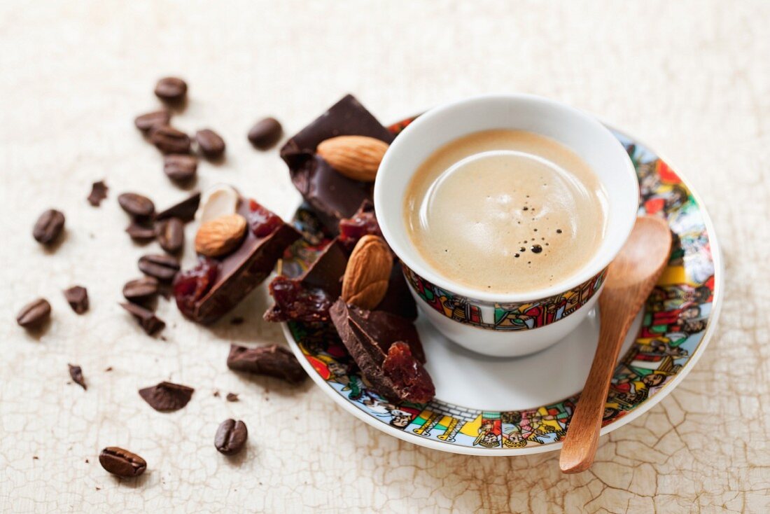 Eine Tasse Espresso und Schokolade mit Trockenfrüchten und Mandeln