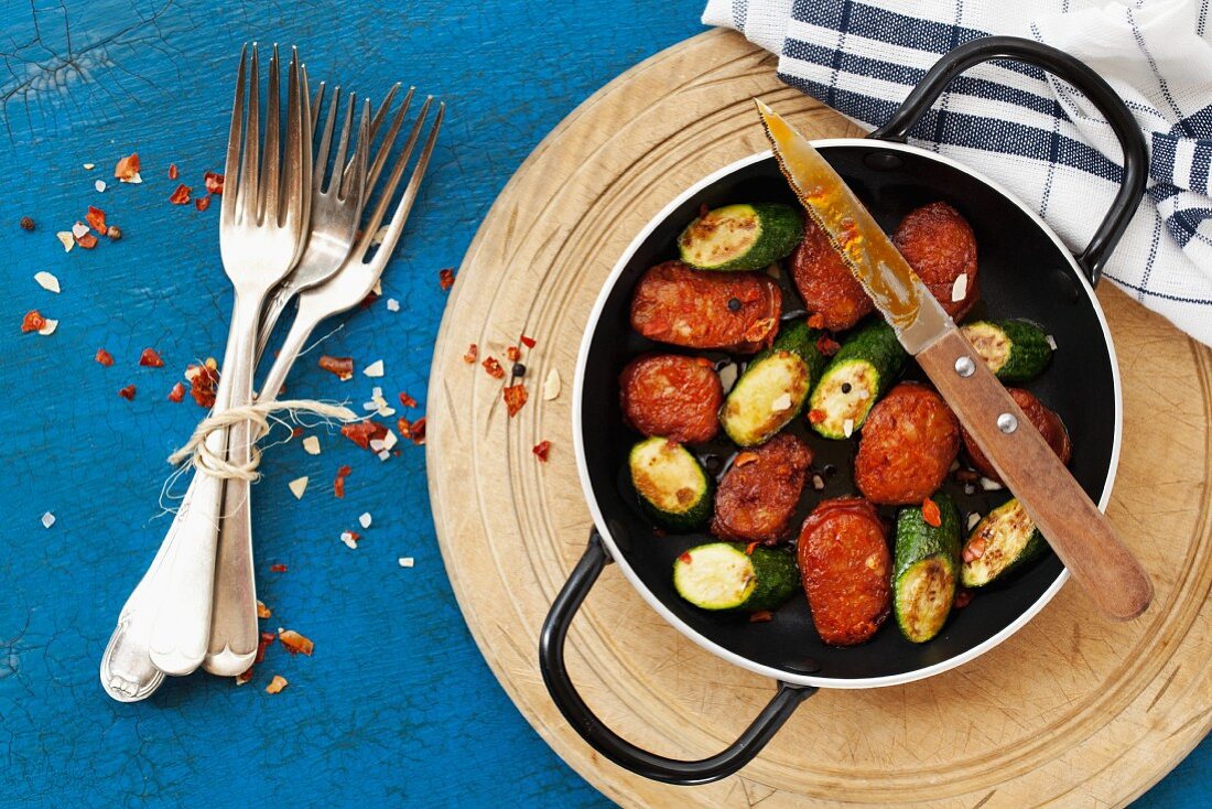 Fried chorizo and courgette slices with chilli flakes in a frying pan