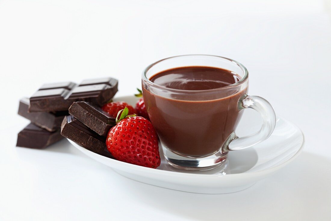 A small cup of thick Italian hot chocolate with strawberries and squares of dark chocolate
