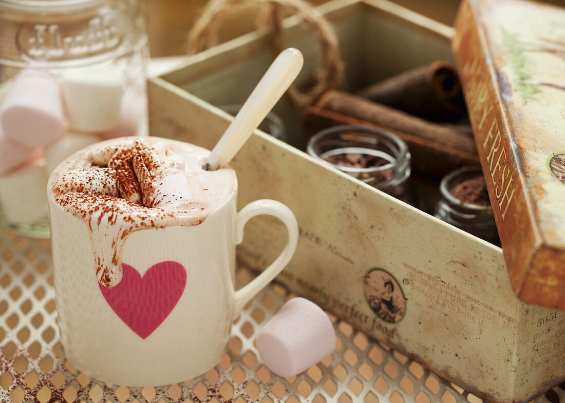 Heiße Schokolade mit Marshmallows in einem Becher mit rosa Herz und tropfender Sahne