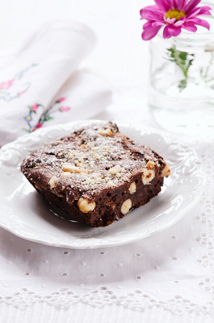 A brownie with nuts and icing sugar