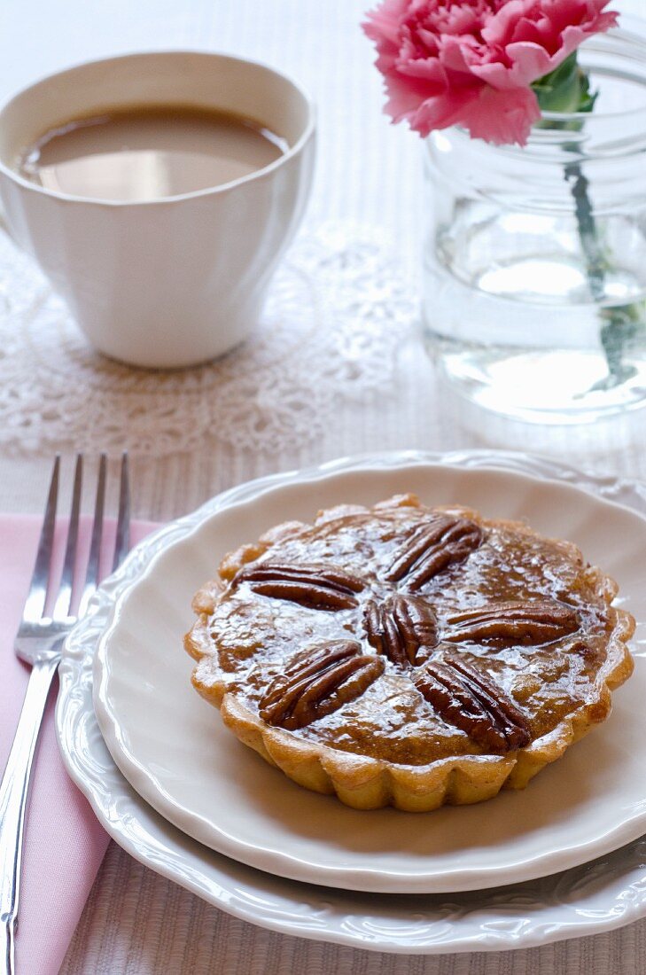 A mini pecan pie with a cup of coffee