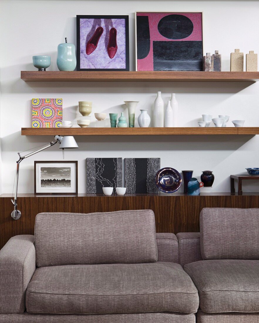 Kunstsammlung, Keramikvasen und Schalen auf Sideboard; im Vordergrund bequemes Designer- Sofa