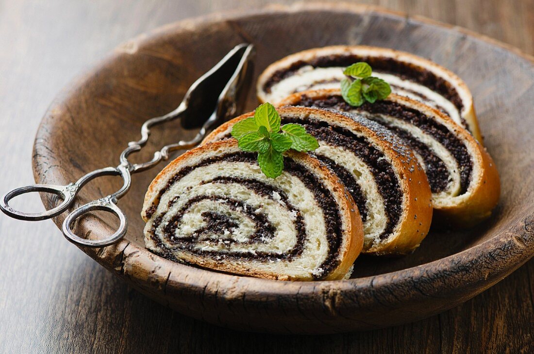 Four slices of poppyseed strudel in a wooden dish