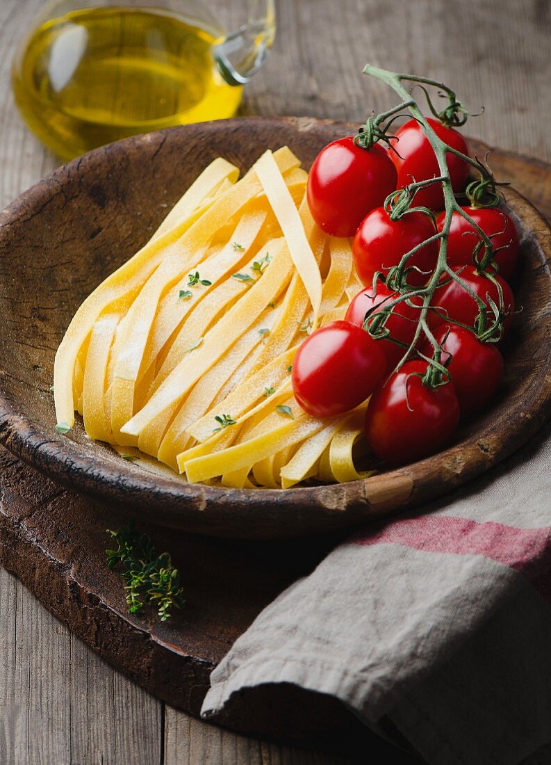 Tagliatelle and cherry tomatoes in a wooden bowl