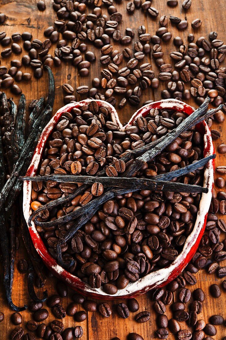 Coffee beans with vanilla pods in a ceramic heart