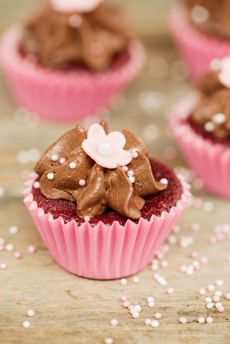 Schokoladencupcake mit Zuckerperlen und Zuckerblume