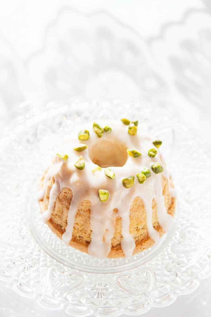 A mini Bundt cake decorated with icing sugar and pistachio nuts