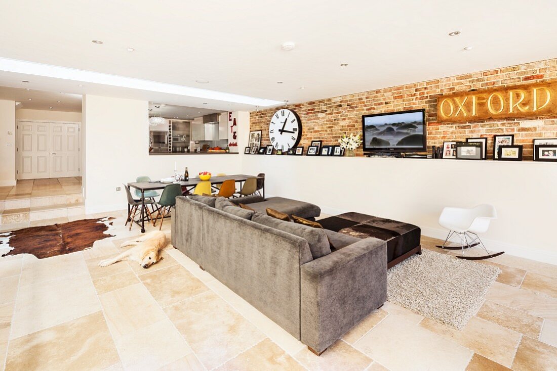 Extended, open-plan, modern living area with exposed brickwork, stone flagged floor and view into raised kitchen
