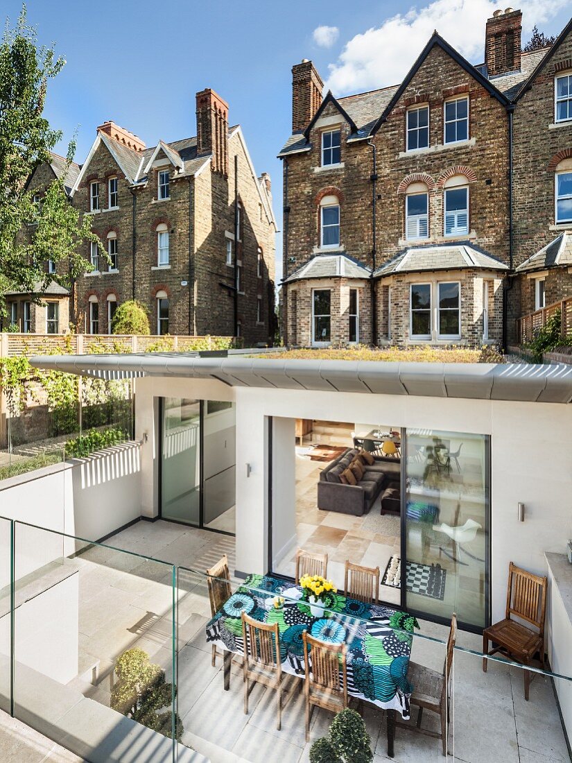 Modern extension of Victorian country house with green roof, sunken living area and terrace with glass balustrade