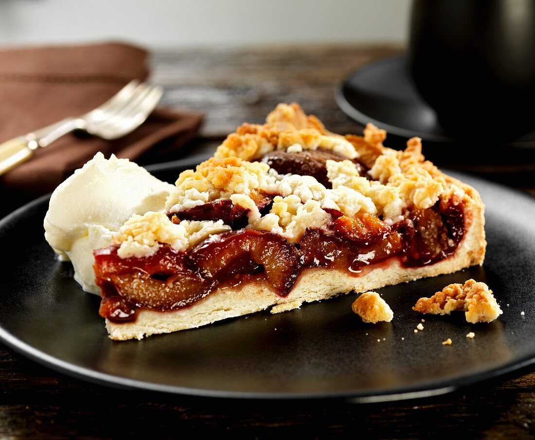 Ein Stück Pflaumen-Streusel-Kuchen mit Sahne