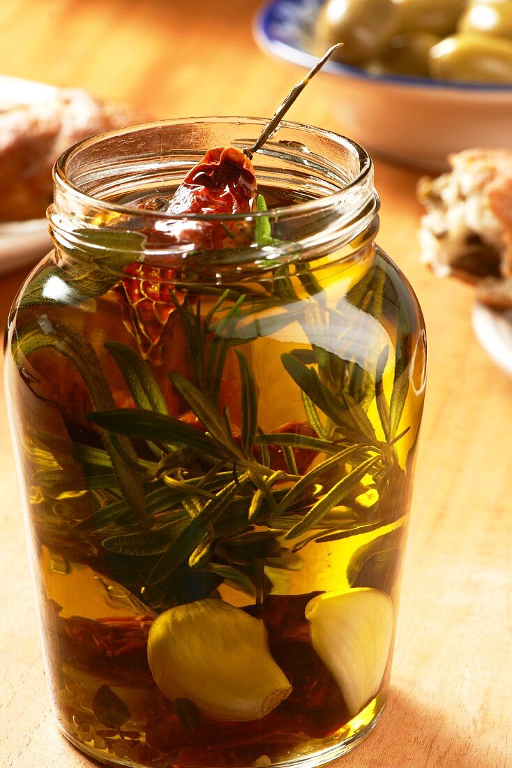 Olivenöl mit Kräutern, Knoblauch und getrockneten Tomaten im Schraubglas