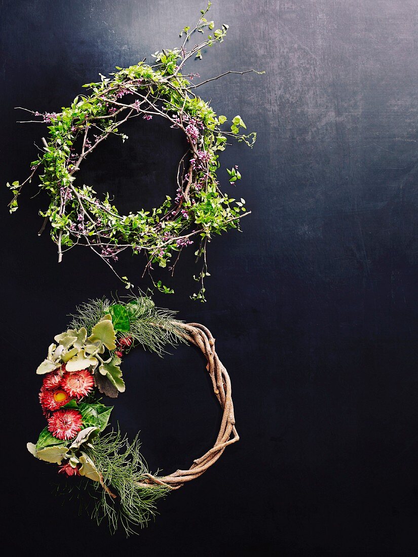 Wreaths of twigs and flowers on dark surface