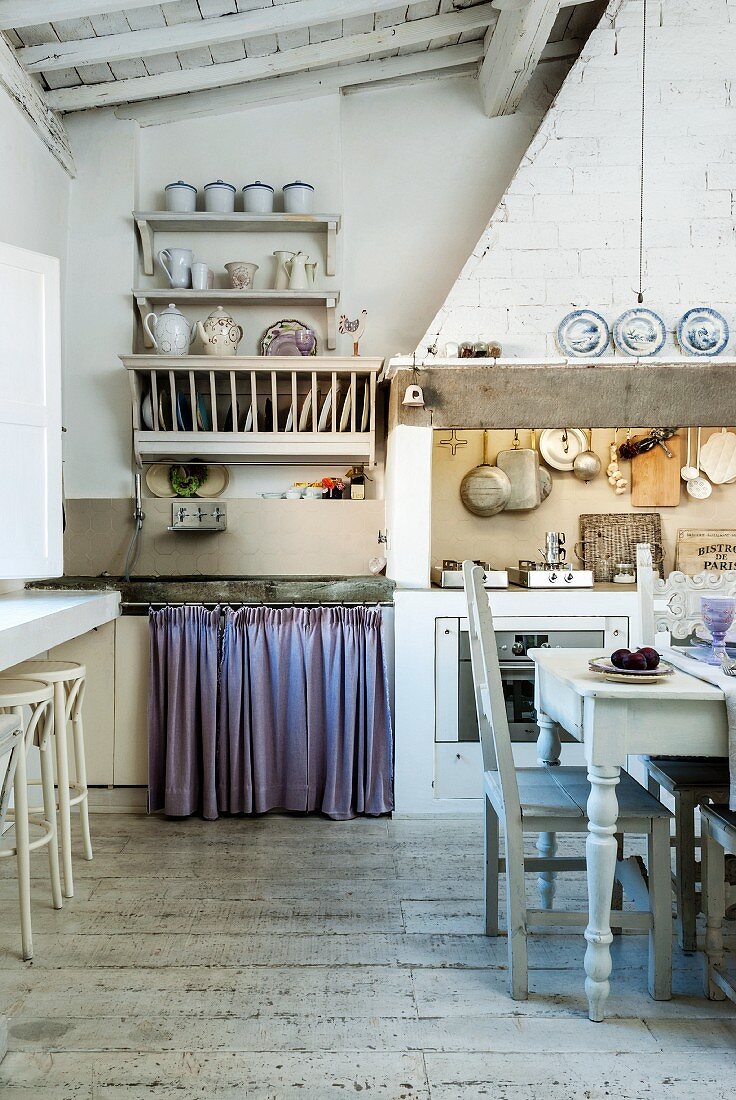 Rustic vintage kitchen with dining area in front of cooker below masonry extractor hood