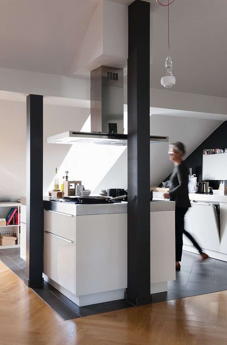 https://media02.stockfood.com/largepreviews/MzQ4ODA0ODM5/11251769-Kitchen-area-in-converted-attic-woman-at-white-island-counter-on-grey-tiled-floor-behind-black-painted-wooden.jpg