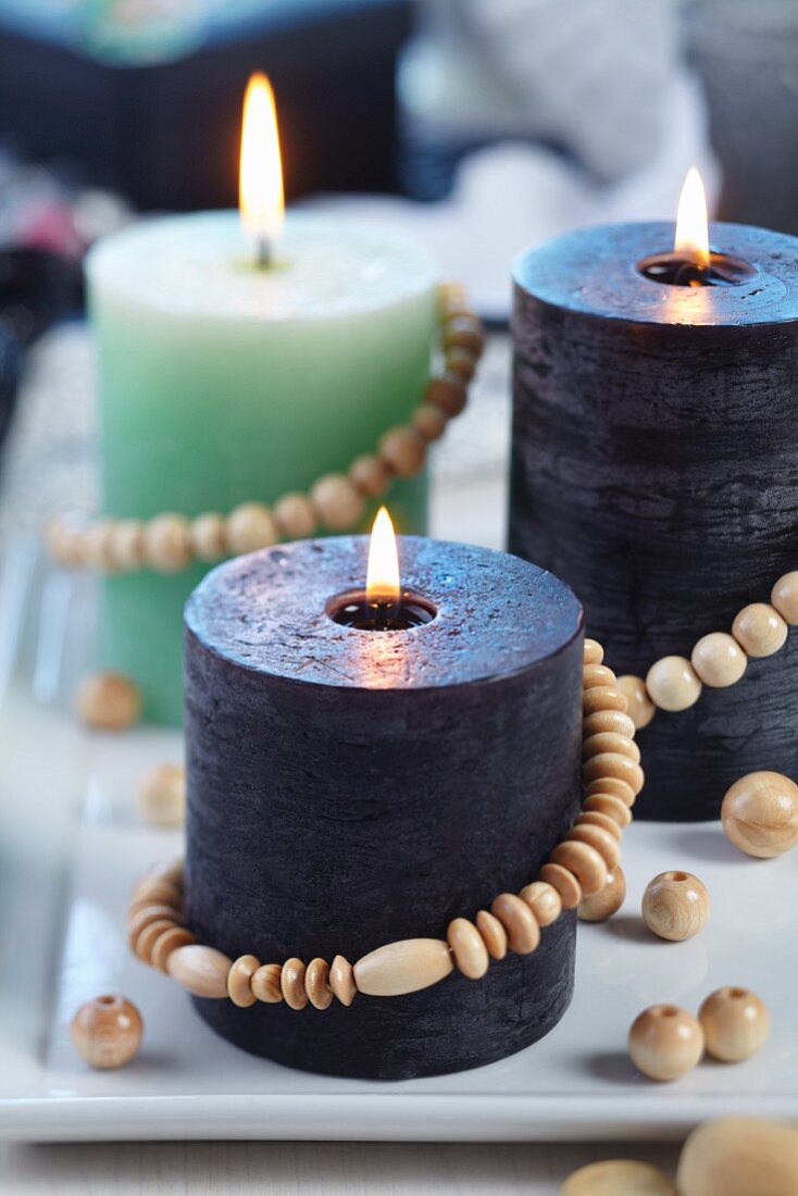 Various candles decorated with strings of wooden beads