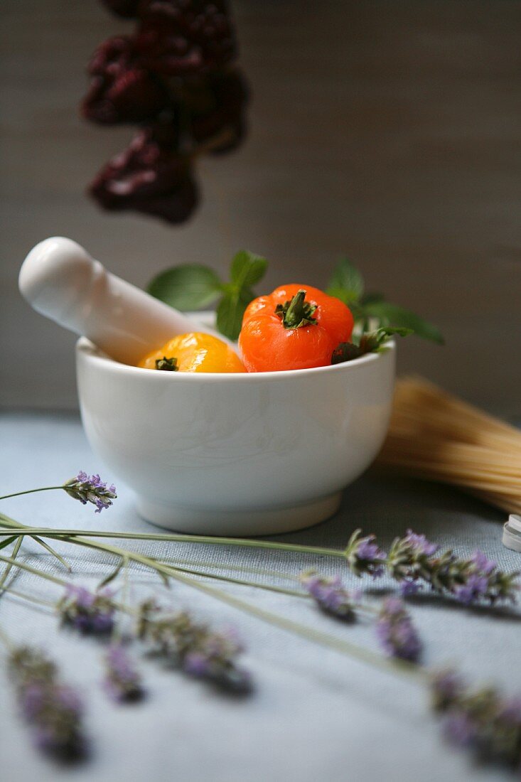 An arrangement featuring white mortar, lavender and fresh and dried peppers