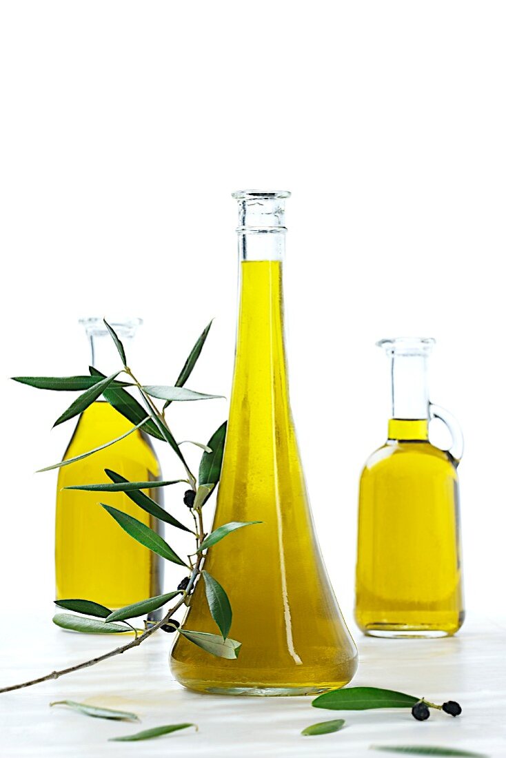 Three bottles of olive oil with an olive sprig