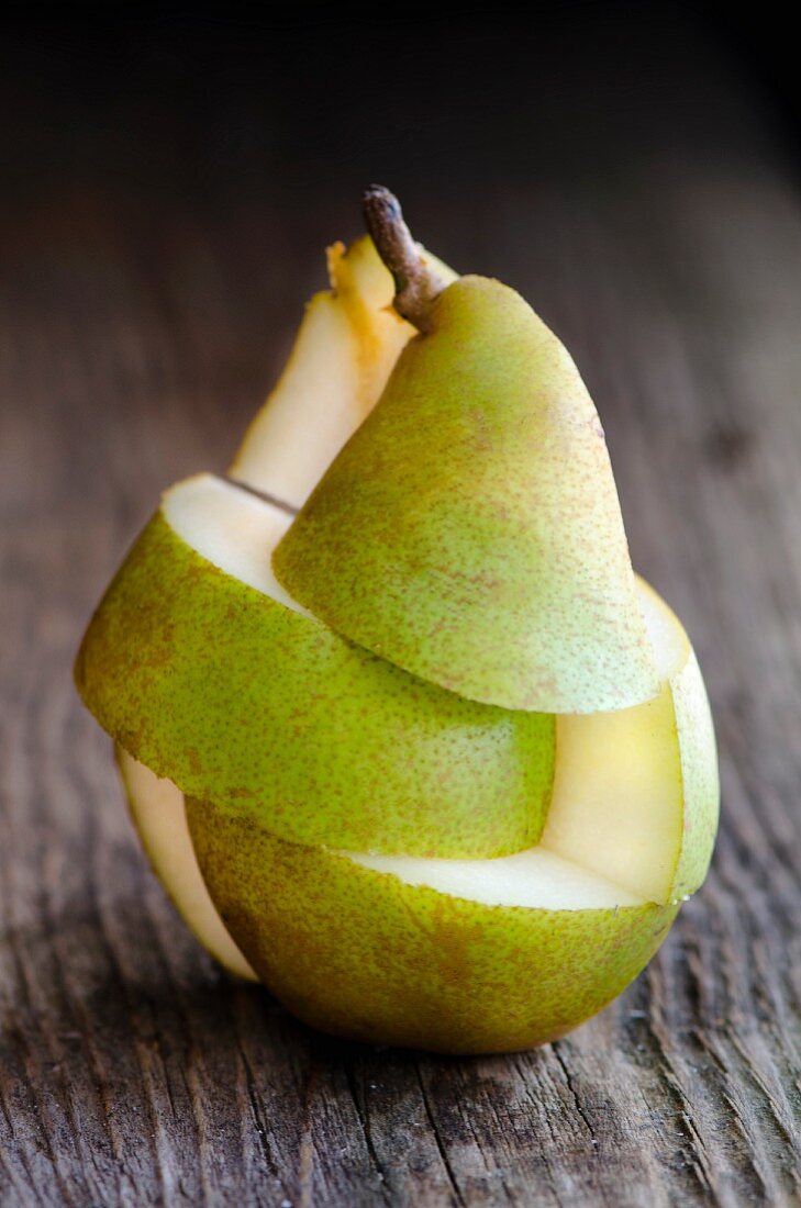 A whole pear, cut into segments, on a wooden surface