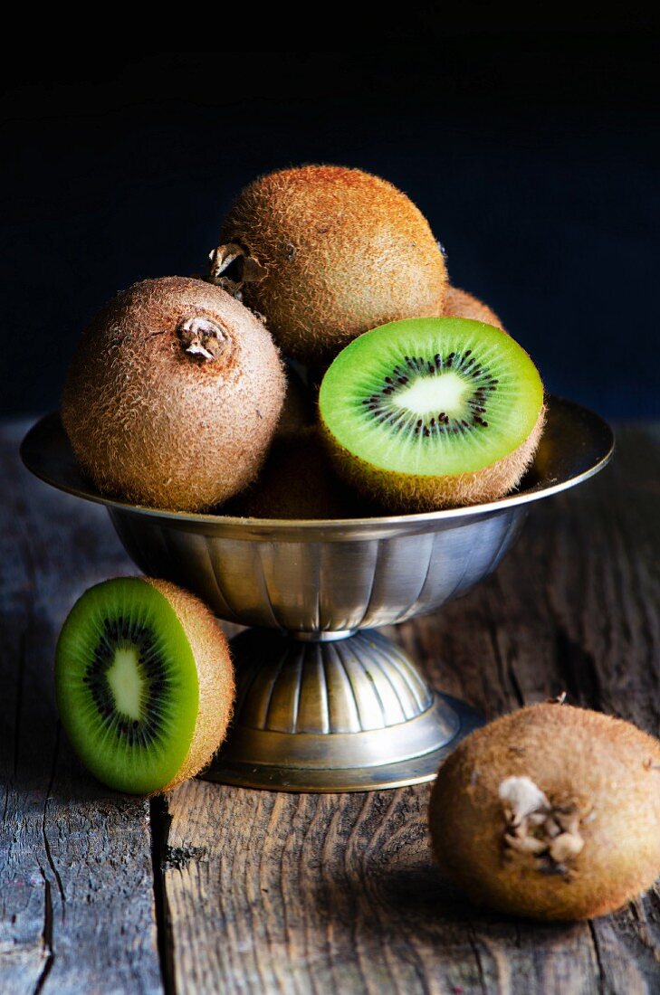 Kiwis, whole and halved, in a metal bowl