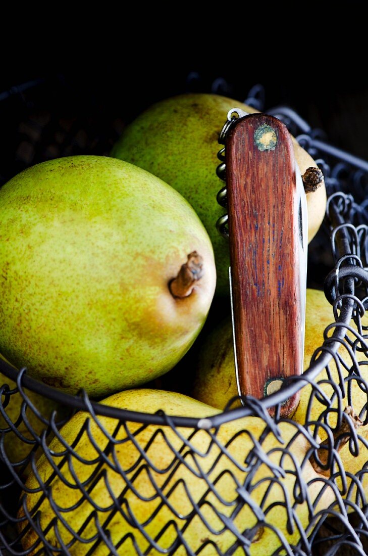 Pears in a wire basket with a knife
