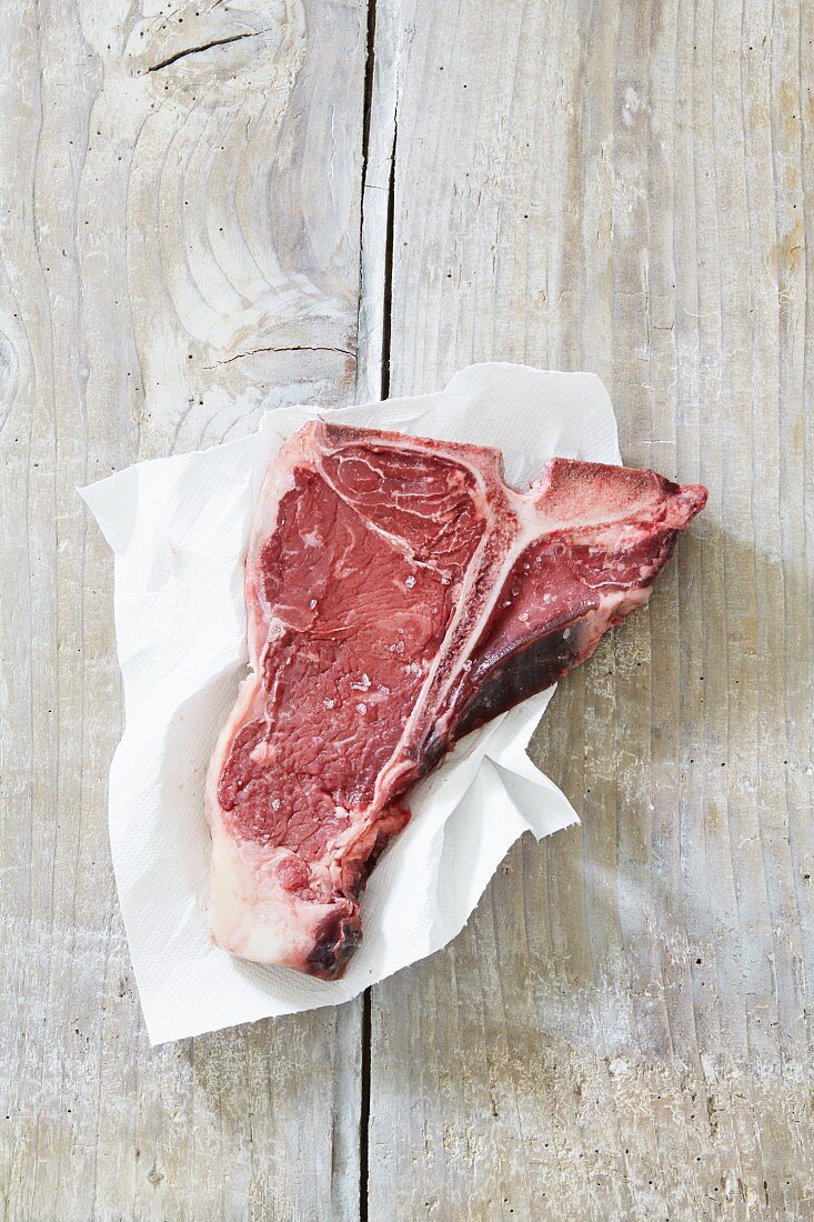 A raw T-bone steak on a piece of paper
