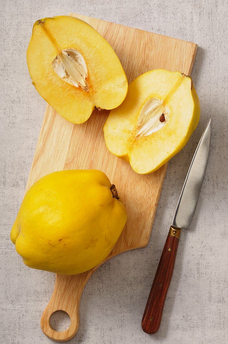Quinces, whole and halved, on a chopping board